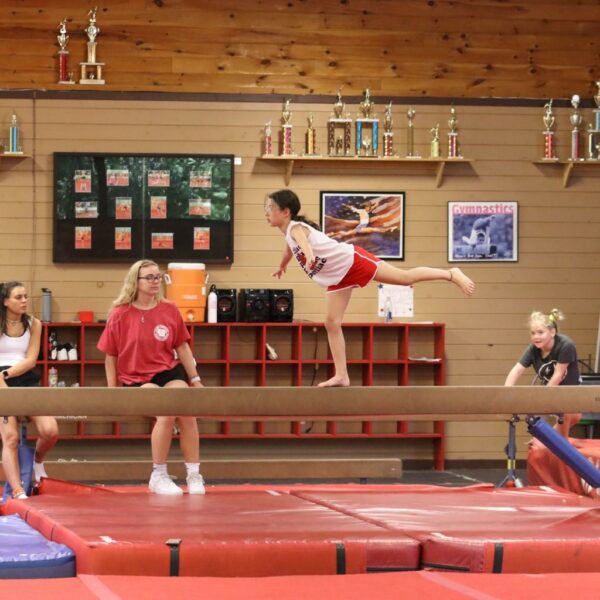 Young girl on the balance beam standing on one foot