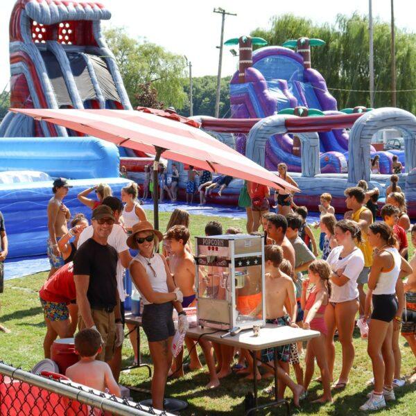 Kids wait in line for popcorn, with fun activities in the background