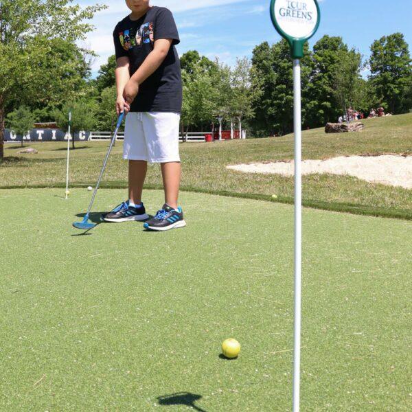 Boy makes a mini golf putt