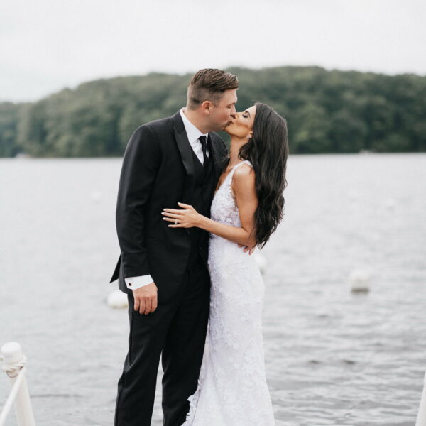 2 newlyweds kissing in front of a lake