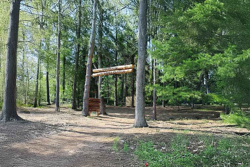 Low ropes course entrance signage in the woods