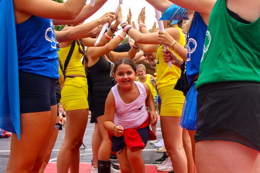 Girl going under bridge of arms made by older girls