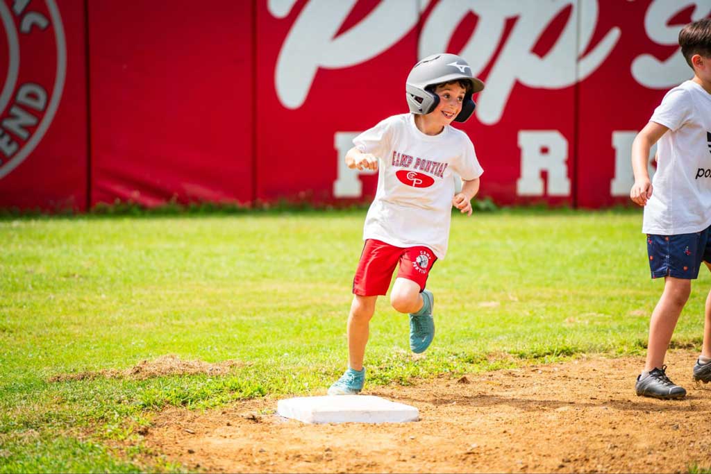 Young boy rounds second base with a smile