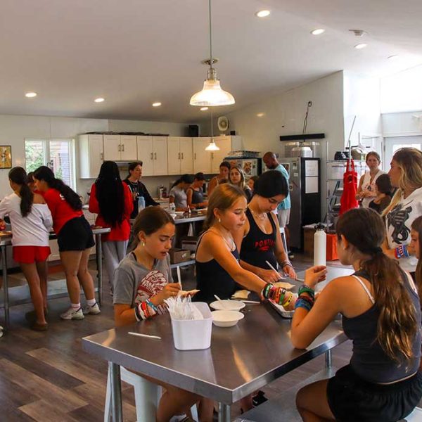 Cooking class for campers in modern kitchen with stainless countertops.